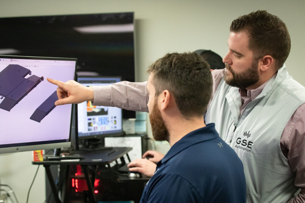 Two men looking at computer screen talking